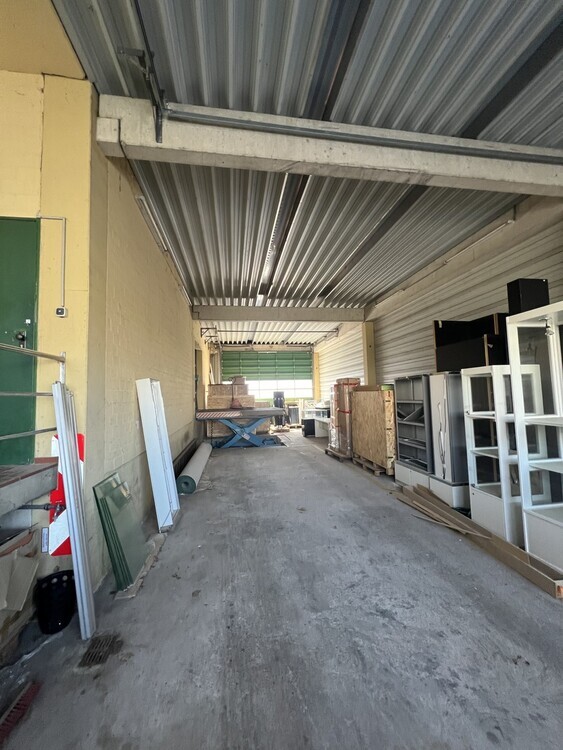 Lagerhalle mit überdachter Ladezone und großem Außenbereich.